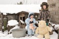 Two happy children in winter fashion clothes ride a sleigh with a toy pig and a bear on a bridge across the river. First snow, fam Royalty Free Stock Photo