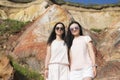 Two happy chinese women standing near rainbow colored cliffs
