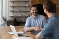 Two happy confident businessmen shaking hands at workplace