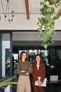 Two happy smiling business women standing at work in office. Vertical portrait. Royalty Free Stock Photo