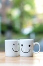 Two happy cups on wood table with bokeh, about love concept Royalty Free Stock Photo