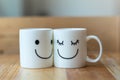 Two happy cups on wood table with bokeh, about love concept Royalty Free Stock Photo