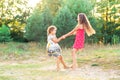 Two Happy cute little girls embracing and dancing at sunny summer day outdoors