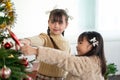 Two happy and cute young Asian girls in cute dresses are having fun and decorating a Christmas tree Royalty Free Stock Photo