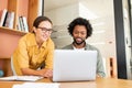 Two happy diverse colleagues African American man and Caucasian woman looking at laptop screen and sitting in office Royalty Free Stock Photo