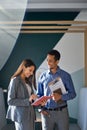 Two happy diverse workers talking standing in office. Vertical shot Royalty Free Stock Photo