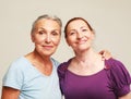 Two happy elderly women friends hugging on grey background. Royalty Free Stock Photo