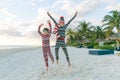 Two happy excited children jumping on sandy beach in Christmas pyjamas