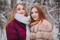 Two happy female friends enjoying snowing weather outdoors, women best friends in winter clothes down jackets laughing