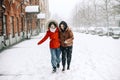 Two happy female friends enjoying snowing weather outdoors, women best friends in winter clothes down jackets laughing