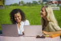 Two happy female friends working outdoors at beautiful internet cafe with laptop computer caucasian woman and an afro mixed girl Royalty Free Stock Photo