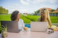 Two happy female friends working outdoors at beautiful internet cafe with laptop computer caucasian woman and an afro mixed girl Royalty Free Stock Photo