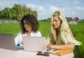 Two happy female friends working outdoors at beautiful internet cafe with laptop computer caucasian woman and an afro mixed girl Royalty Free Stock Photo