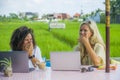 Two happy female friends working outdoors at beautiful internet cafe with laptop computer caucasian woman and an afro mixed girl Royalty Free Stock Photo