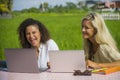 Two happy female friends working outdoors at beautiful internet cafe with laptop computer caucasian woman and an afro mixed girl Royalty Free Stock Photo