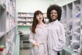 Two happy friendly multiethnic women clinical pharmacists or doctors, posing hugging each other together, smiling to