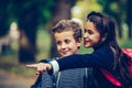 Two happy friends with backpacks looking and pointing with finger away Royalty Free Stock Photo