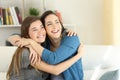 Two happy friends or sisters hugging at home