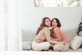 Two happy friends or sisters hugging sitting on a couch in the living room at home Royalty Free Stock Photo