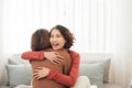 Two happy friends or sisters hugging sitting on a couch in the living room at home Royalty Free Stock Photo