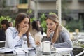 Two happy friends or sisters sharing a smart phone in a coffee shop terrace Royalty Free Stock Photo