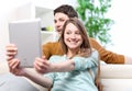 Two happy friends taking photo with tablet pc at home on the couch Royalty Free Stock Photo