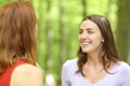 Two happy friends talking in a green forest or park Royalty Free Stock Photo