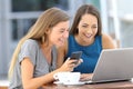 Happy friends using a laptop and phone in a bar Royalty Free Stock Photo