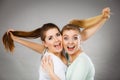 Two happy friends women hugging holding hair Royalty Free Stock Photo