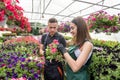 two happy gardeners in aprons work with flowers plants in the nature greenhouse garden Royalty Free Stock Photo