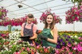 Two happy gardeners in aprons work with flowers plants in the nature greenhouse garden Royalty Free Stock Photo