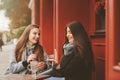 Two happy girl friends talking and drinking coffee in autumn city in cafe Royalty Free Stock Photo