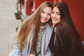 Two happy girl friends talking and drinking coffee in autumn city in cafe. Meeting of good friends, young fashionable students Royalty Free Stock Photo