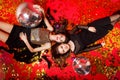 Two happy girlfriends in dresses with makeup and red lips lie on the floor with disco balls and gold confetti Royalty Free Stock Photo