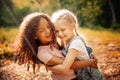 Two happy girls as friends hug each other in cheerful way. Little girlfriends in park.