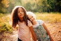 Two happy girls as friends hug each other in cheerful way. Little girlfriends in park.