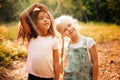 Two happy girls as friends hug each other in cheerful way. Little girlfriends in park. Royalty Free Stock Photo