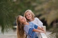 Two happy girls as friends hug each other in cheerful way. Little girlfriends in park. Children Friendship Together Smiling