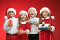 Two happy girls and boys in santa claus hats with gift boxes Royalty Free Stock Photo