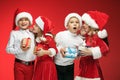 Two happy girls and boys in santa claus hats with gift boxes Royalty Free Stock Photo