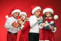 Two happy girls and boys in santa claus hats with gift boxes Royalty Free Stock Photo