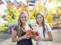 Two happy girls enjoying a cool drink at an amusement park