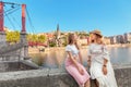 happy girls friends walking on Saint Georges pedestrian bridge while traveling in Lyon old town in France