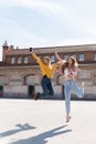 Two happy girls jump in the middle of a square in the street