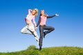 Two happy girls jumping on green meadow Royalty Free Stock Photo