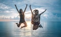 Two happy girls jumping at sunset on tropical beach Royalty Free Stock Photo