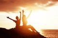 Two happy girls with raised hands against sunset sea Royalty Free Stock Photo