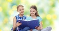 Two happy girls reading book over green background Royalty Free Stock Photo