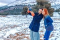 Two happy girls of Slavic appearance, brunette and red-haired, make a selfie on a smartphone, outdoors in the winter