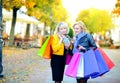 Two happy girls in sunglasses with shopping bags, use a smartphone and smile Royalty Free Stock Photo